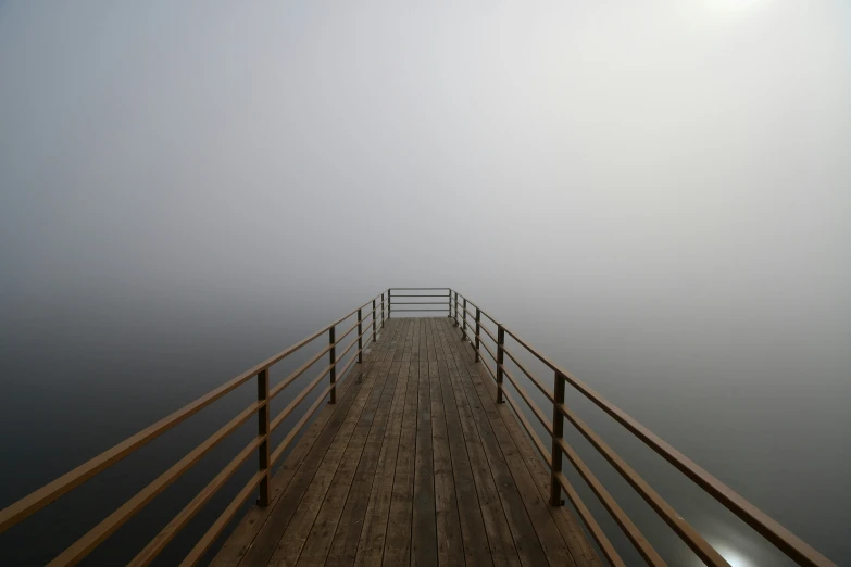 an empty pier on a foggy day near the sea