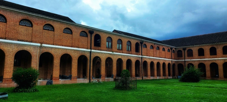 a brick building with arches and grass in the courtyard