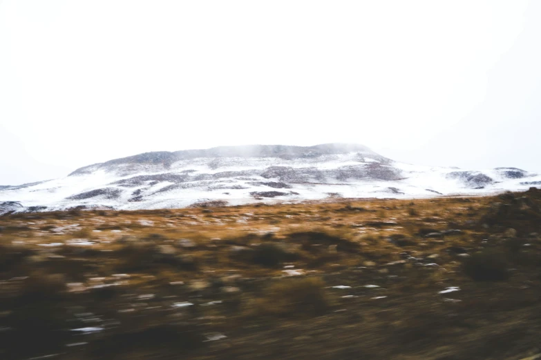 a hill covered with brown grass and some snow