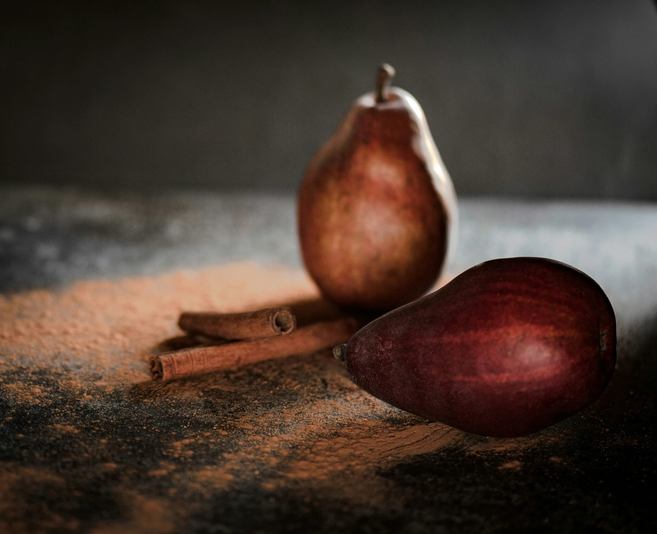 two apples on a surface near cinnamon sticks