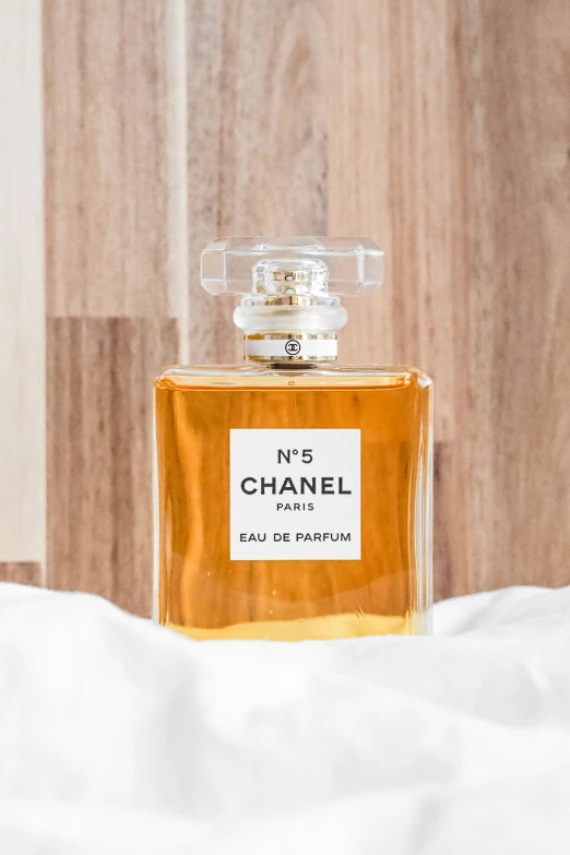 a bottle of perfume sitting on top of white sheets