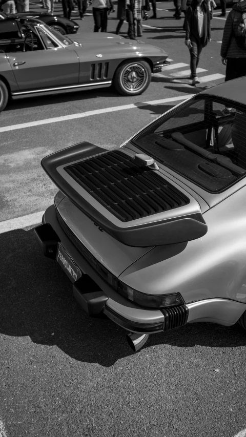 an old convertible sits on the road by some cars