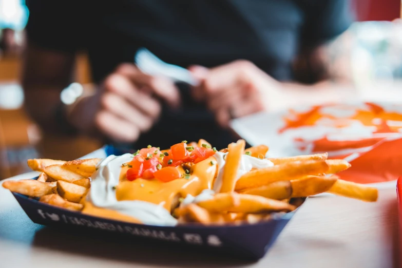 a tray filled with fries next to another container