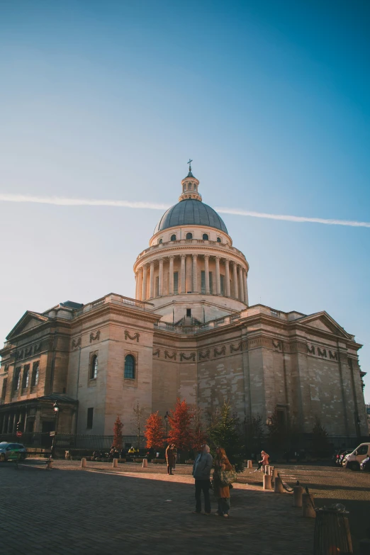 there are people walking by the dome of this old building