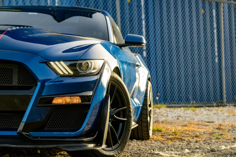 a blue sports car in front of a fence