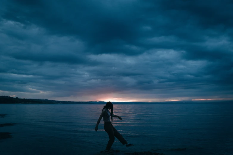 a young person walking on a beach near the ocean