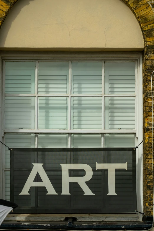 a large black sign that says art with shutters and a brick window