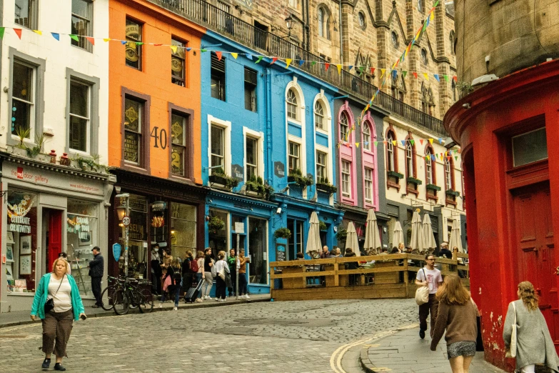 the people are walking down the street near many shops