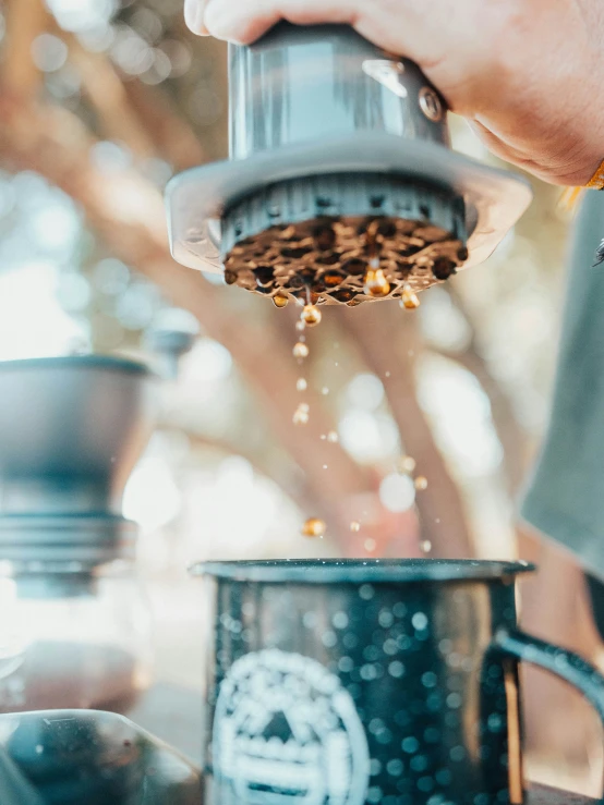 a person pouring coffee from a to - go cup into the bottom of a coffee pot