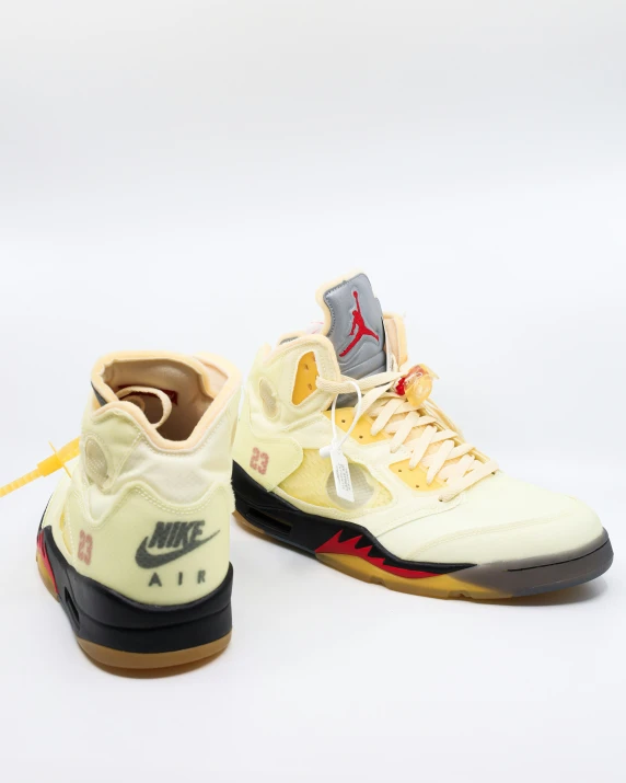 the white and yellow nike air jordan sneaker has a red arrow on it