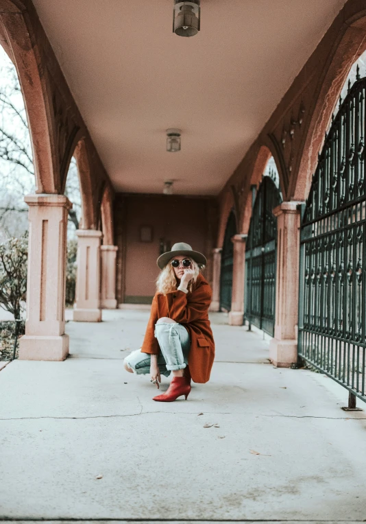 a woman kneeling down on the sidewalk in a brown coat