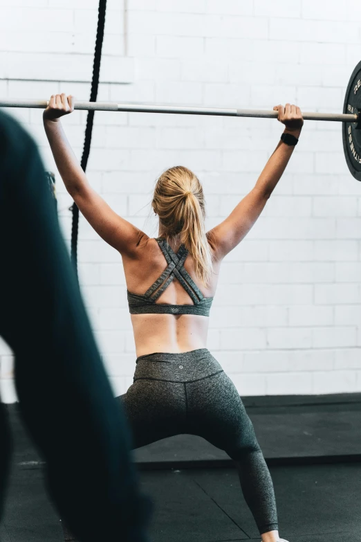 a woman is performing the squat exercises on a bar