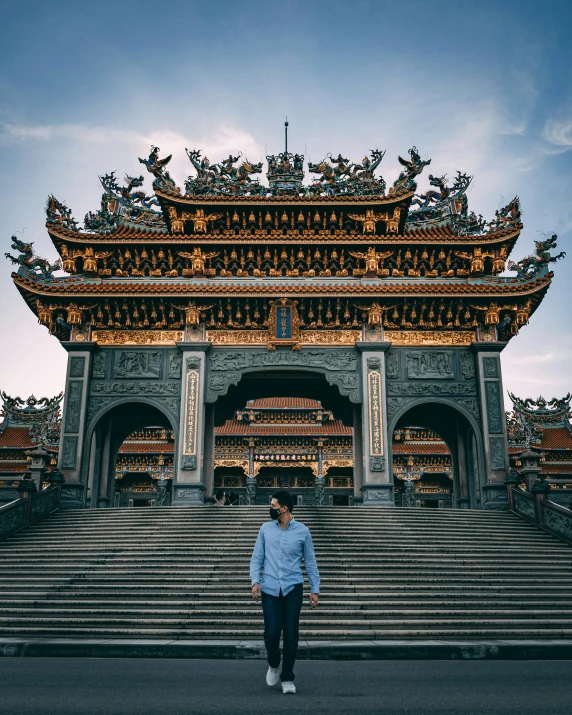 a woman walking across the street in front of a large chinese style gate