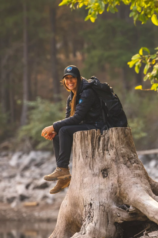 a young lady sitting on top of a wooden tree stump