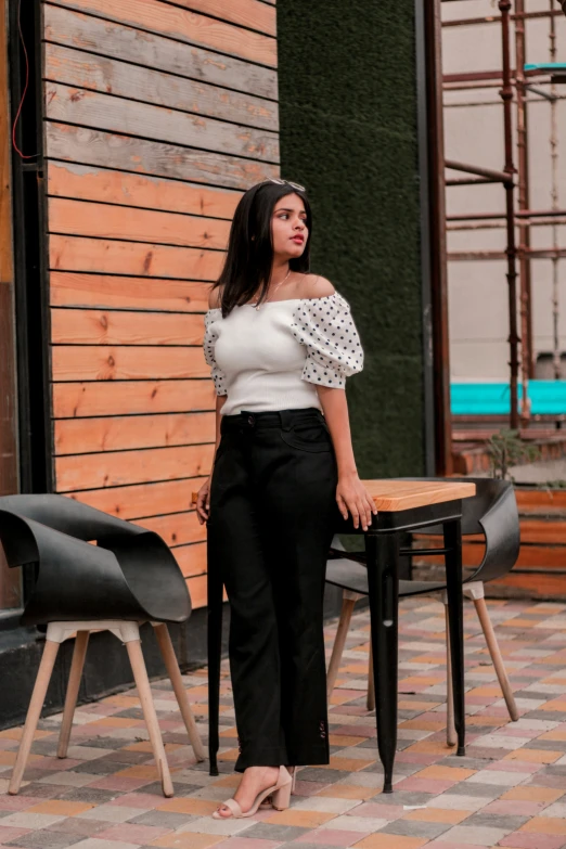 a woman wearing a white top is standing in front of a table