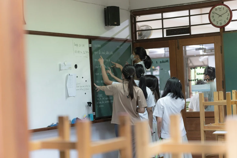 people are standing in a class room writing on a white board