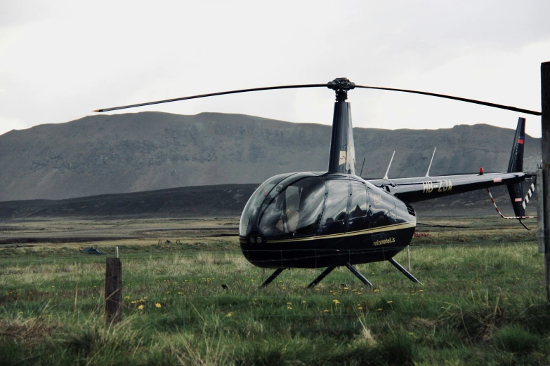 a helicopter parked next to a fence in a grassy field