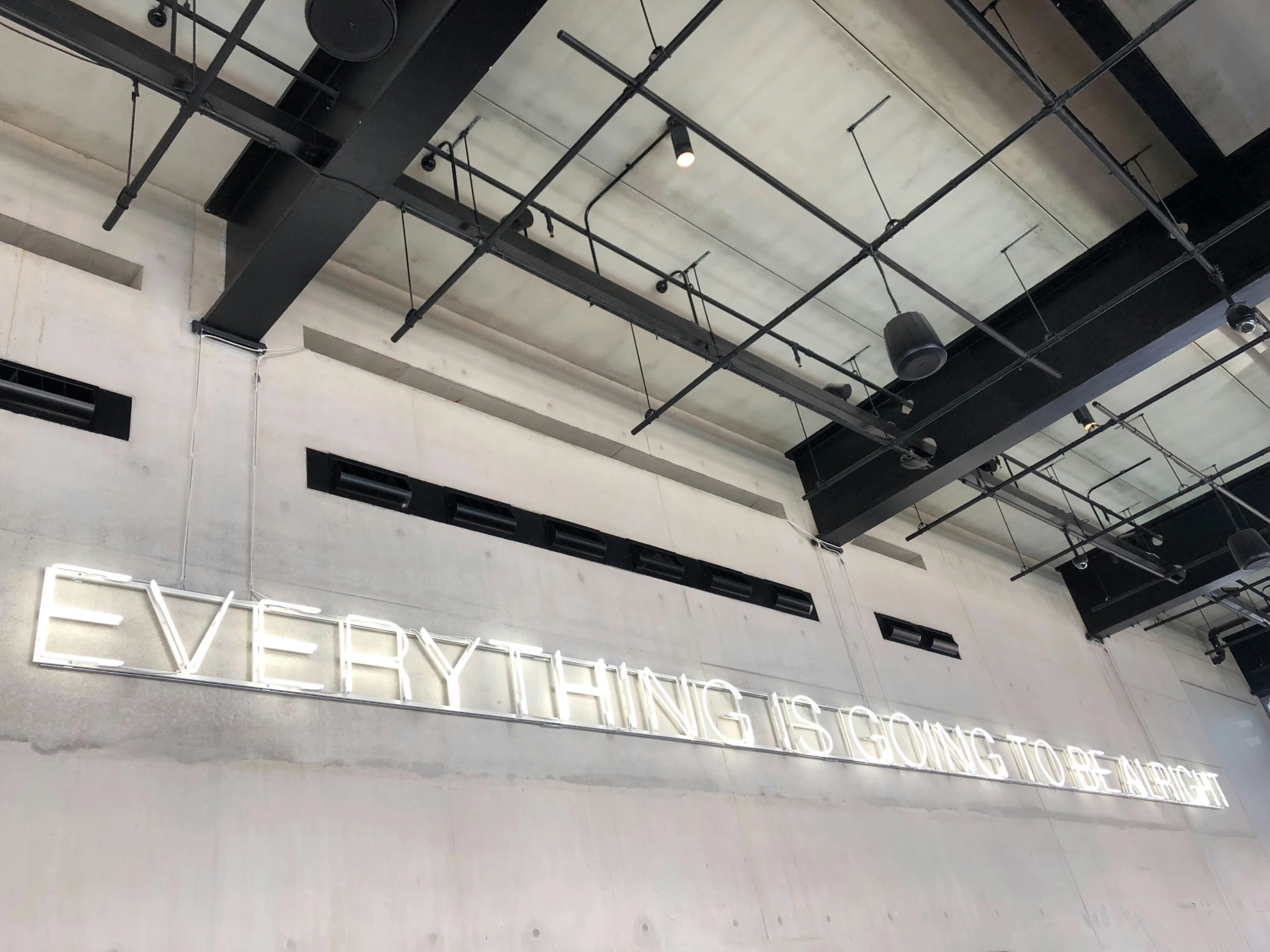 a po of the exterior of a building with neon signs on the wall reading everything is contained inside