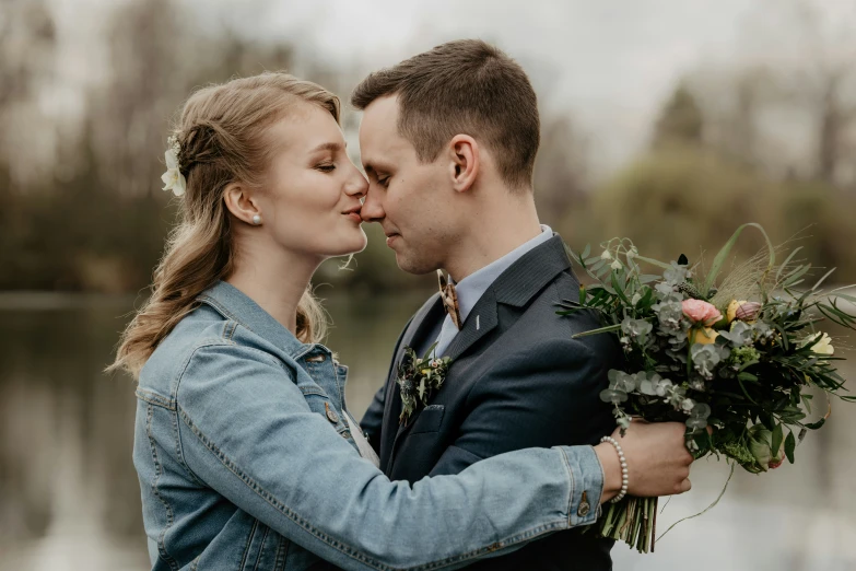 an attractive couple in front of a lake hugging