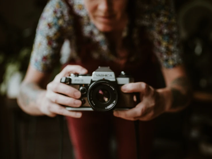 a lady holding a camera looking at the lens