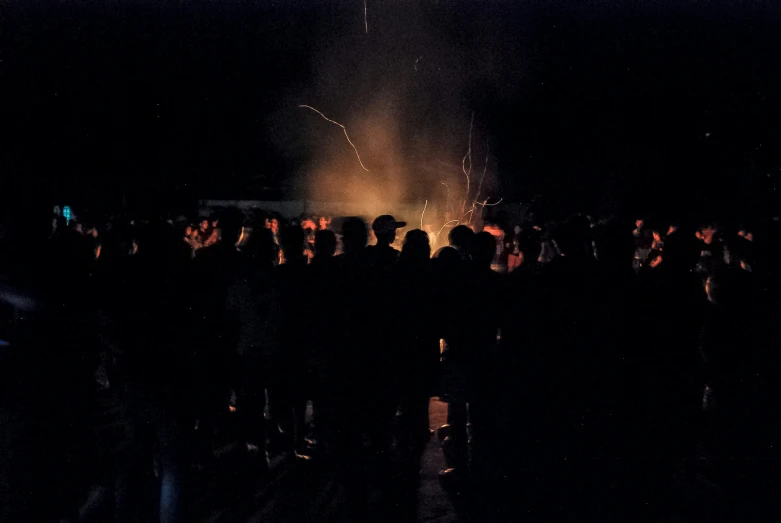 people in a dark crowd looking at a firework