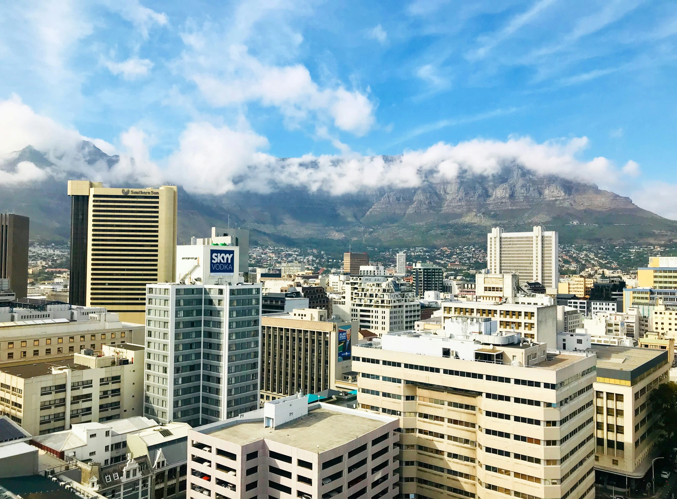 buildings and mountains surround the city, as seen from an elevated viewpoint