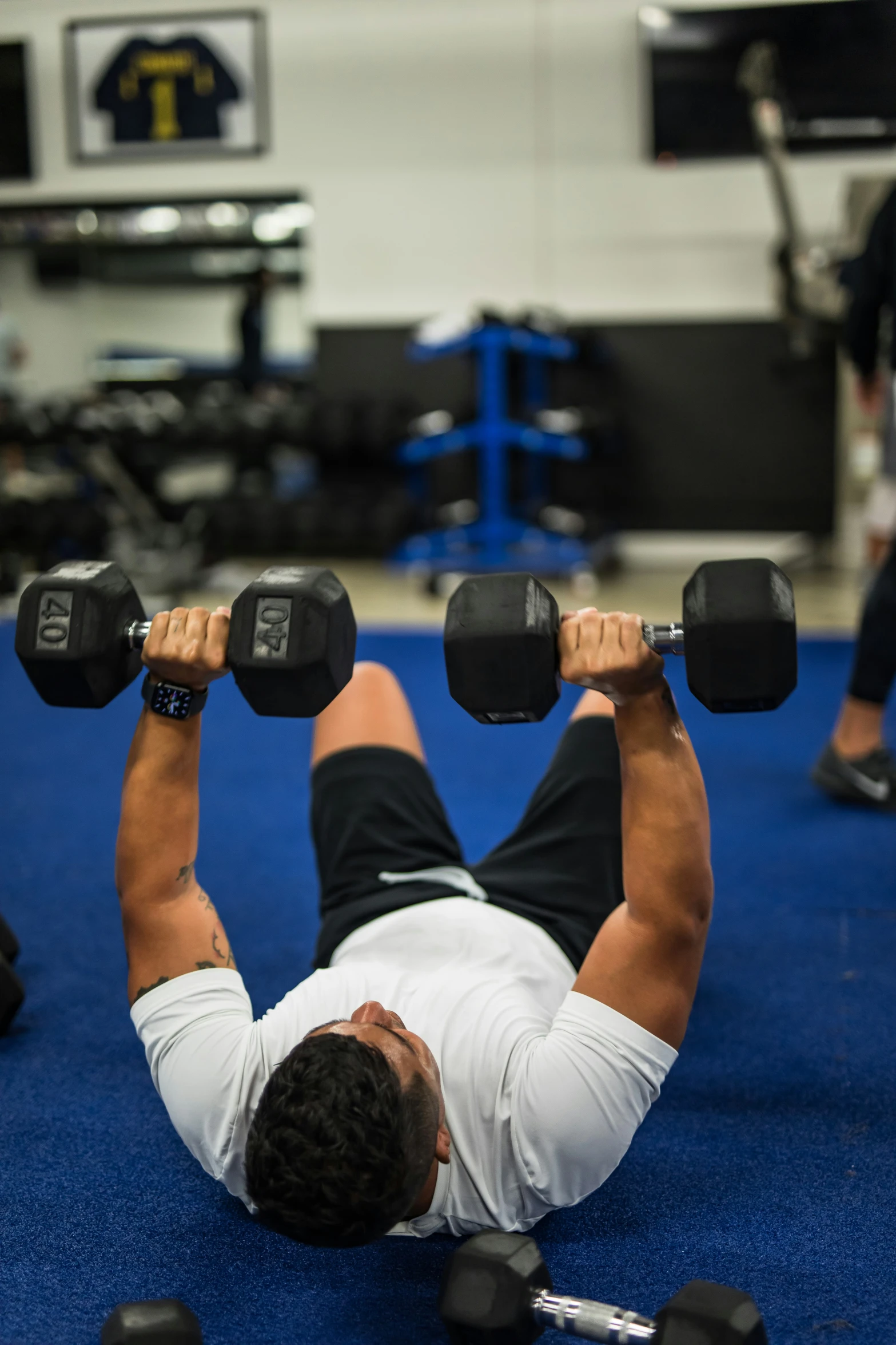 a man laying on the ground with dumbbells