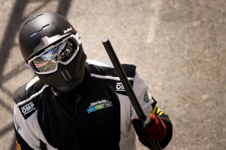 a person in a motorcycle helmet holds a stick