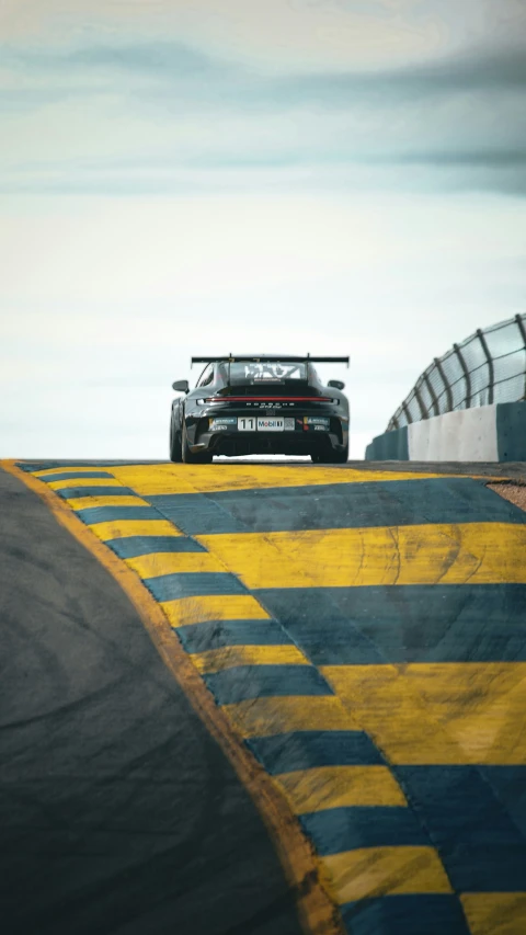 a black car driving along the side of a race track