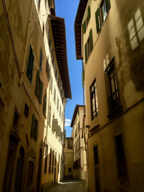 an alley with green shuttered windows is seen from the inside