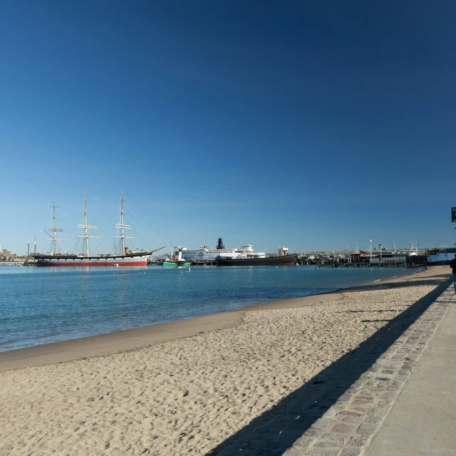 a sail boat sitting out in the water at a pier