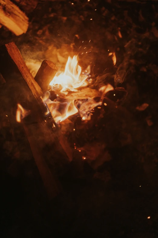 a fire burns in the dark next to a fire with a wood plank on it