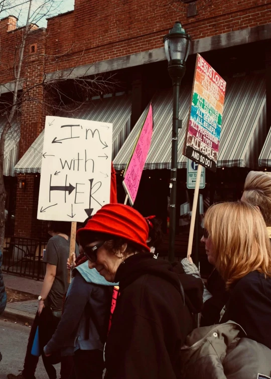 people with signs are walking by a row of shops