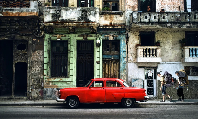 a vintage car is parked in front of dilapidated buildings