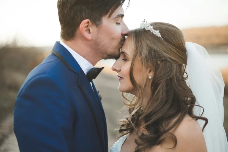 a man and a woman wearing formal wear kissing