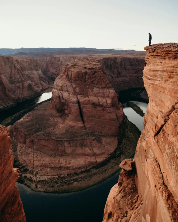 a man on top of an cliff overlooking a lake