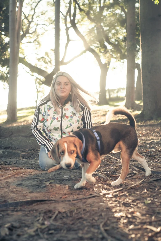 a woman poses in the woods with her dog