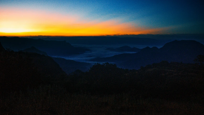 the sun is setting over mountains in a very hazy sky