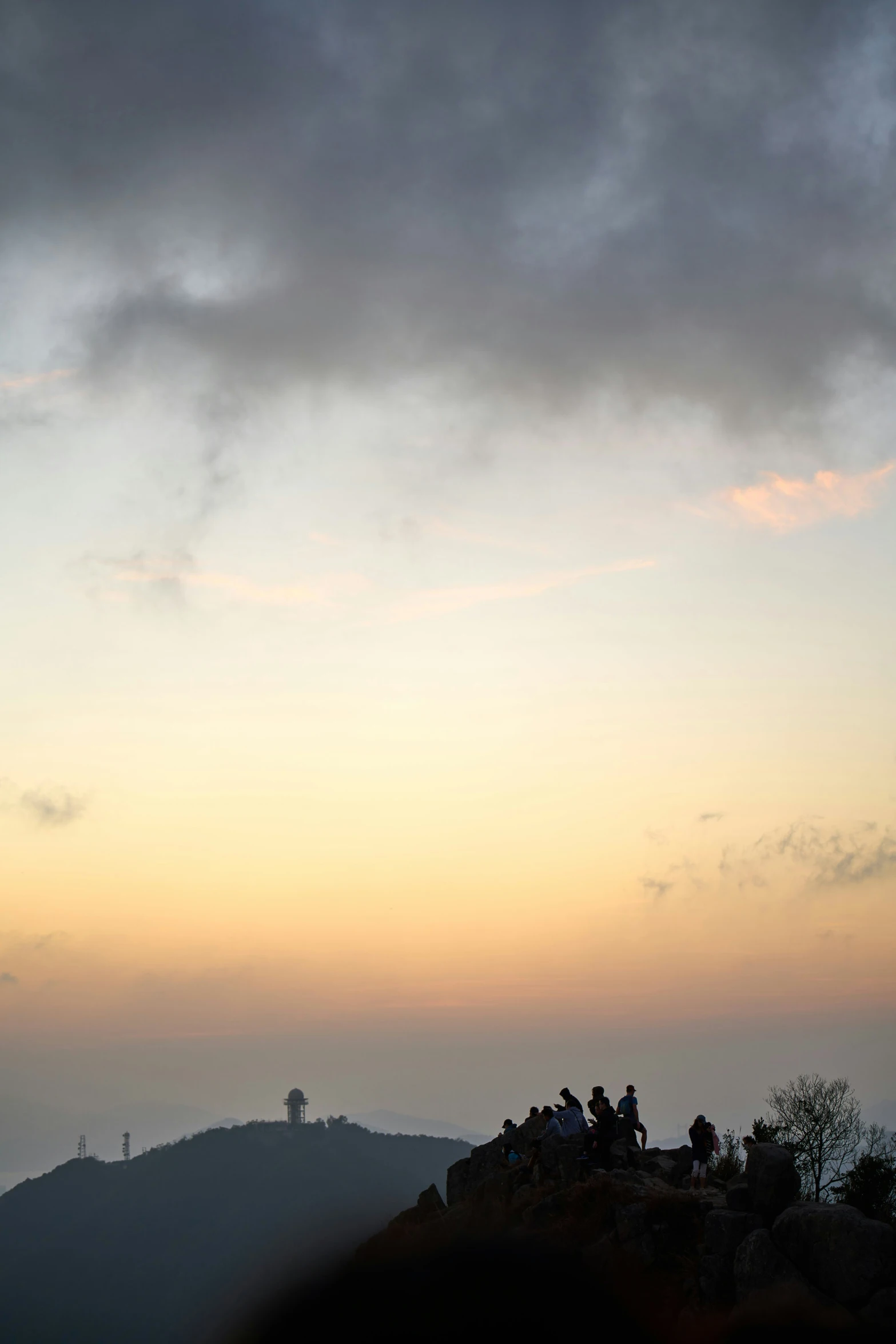 a group of people standing on top of a hill with the sun setting