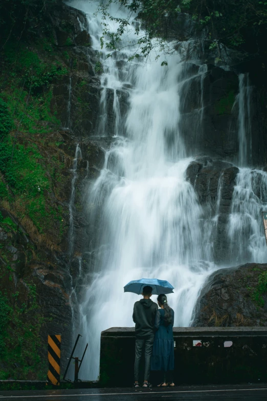 a couple with an umbrella watching the waterfall