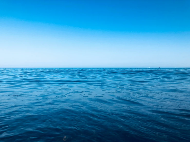 a very distant beach with calm waters and a sky