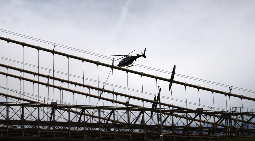 a person hanging onto the side of a bridge while attached to ropes