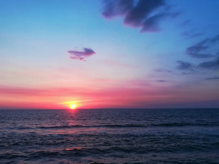 the sun setting over a calm beach during sunset