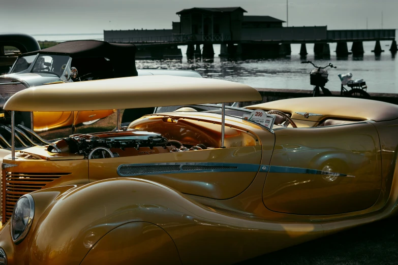 an orange vintage car parked next to a body of water