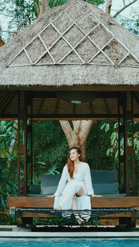 woman sitting on bench near large pool in natural setting