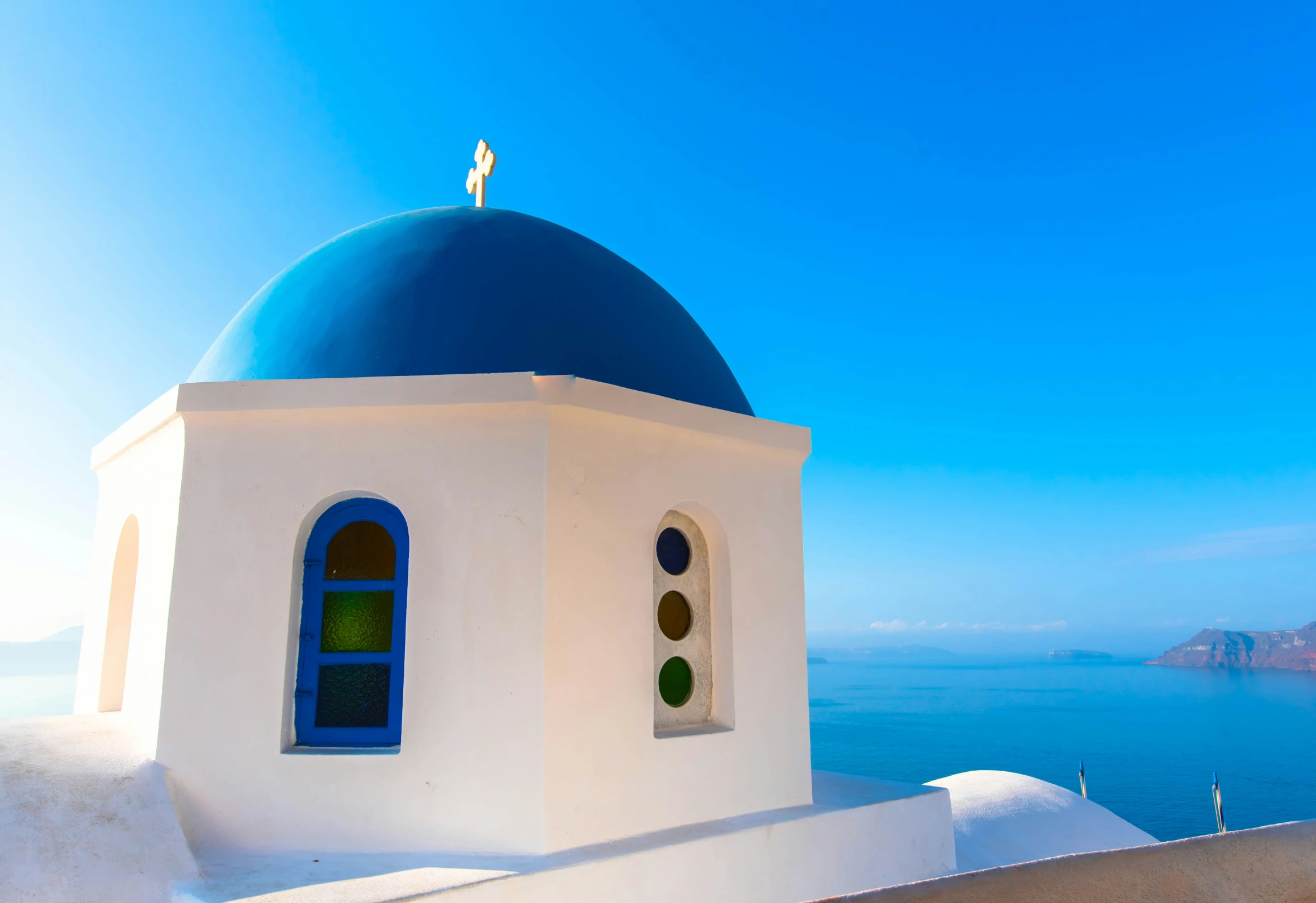 a church on the edge of a cliff with a blue dome