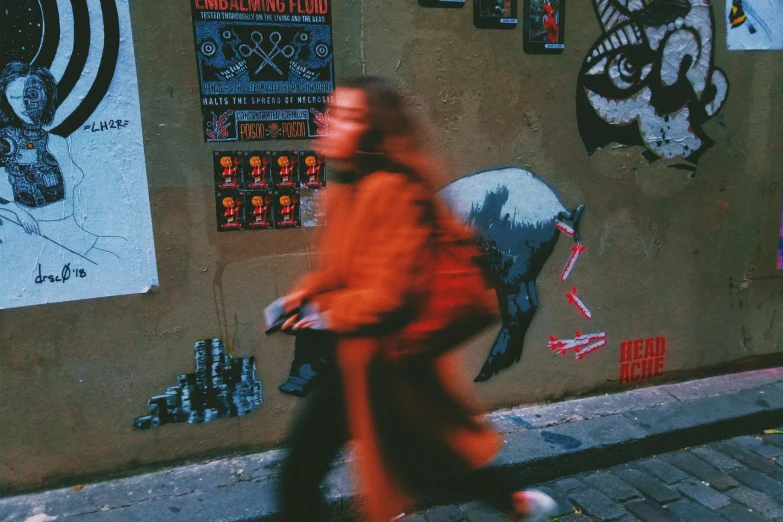 a person walking on a street next to paintings