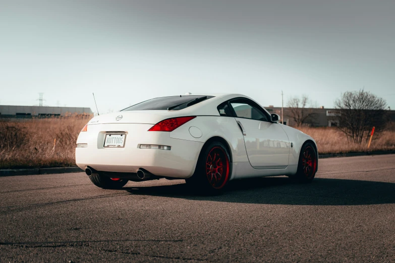 a white nissan car on a road near bushes