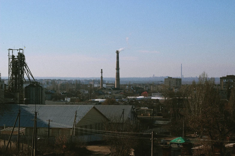 a smokestack sitting in the distance from an industrial area