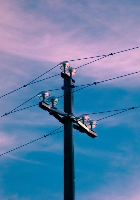 an overhead electrical wire with four lights and a sky background